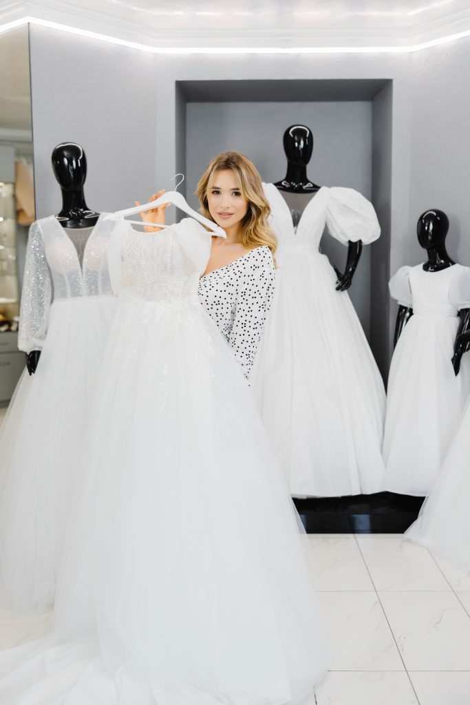 Young beautiful woman chooses a dress for wedding in a wedding salon.